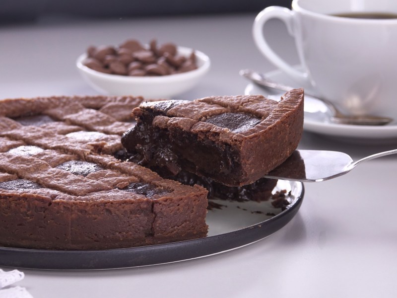 Mousse-au-Chocolat-Kuchen, aus dem ein Stück herausgenommen wird, dahinter eine Kaffeetasse.