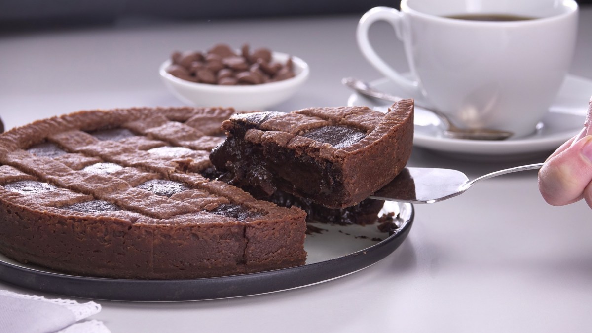 Mousse-au-Chocolat-Kuchen, aus dem ein Stück herausgenommen wird, dahinter eine Kaffeetasse.