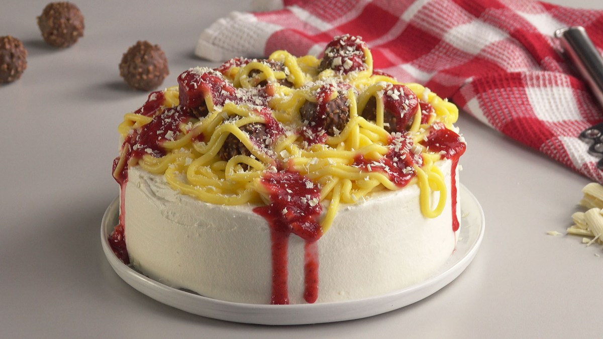 Eine süße Spaghetti-Torte mit Nudeln aus Pudding, Erdbeersoße und Rocher als Fleischbällchen.
