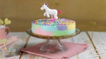 Ein bunter Einhorn-Kuchen auf einer Kuchenplatte.