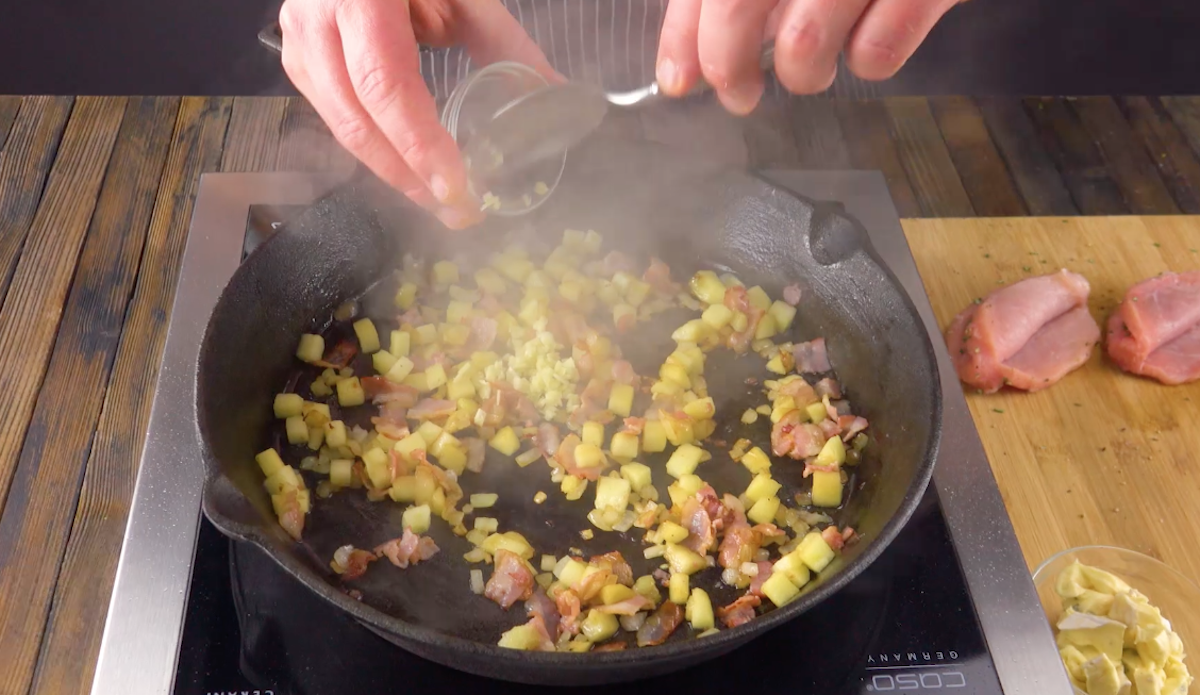 Klein geschnittener Bacon, Apfel und Zwiebel werden in einer Pfanne angebraten