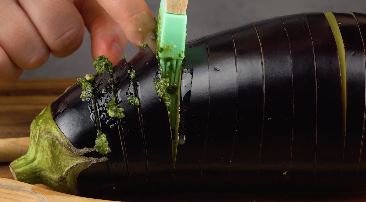 Die Einschnitte in der Aubergine werden mit grÃ¼nem pesto gefÃ¼llt.  