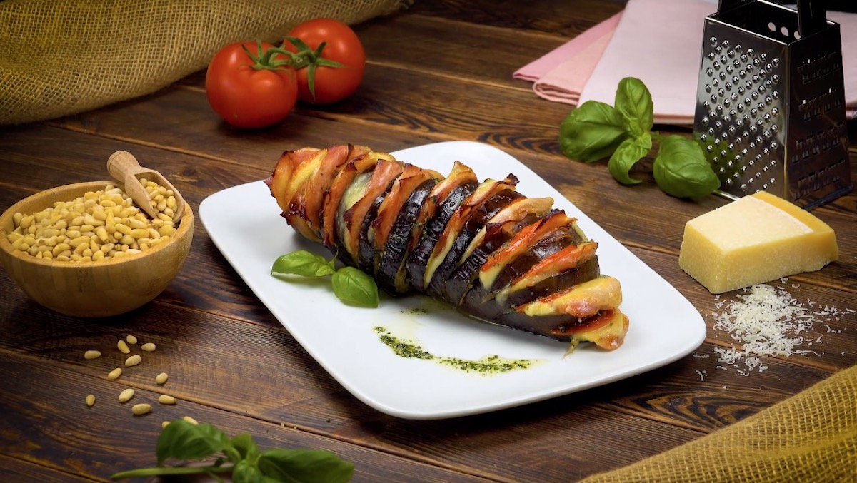 Aubergine Ã  la Hasselback, mit Kochschinken und Tomaten gefÃ¼llt, auf weiÃŸem Teller