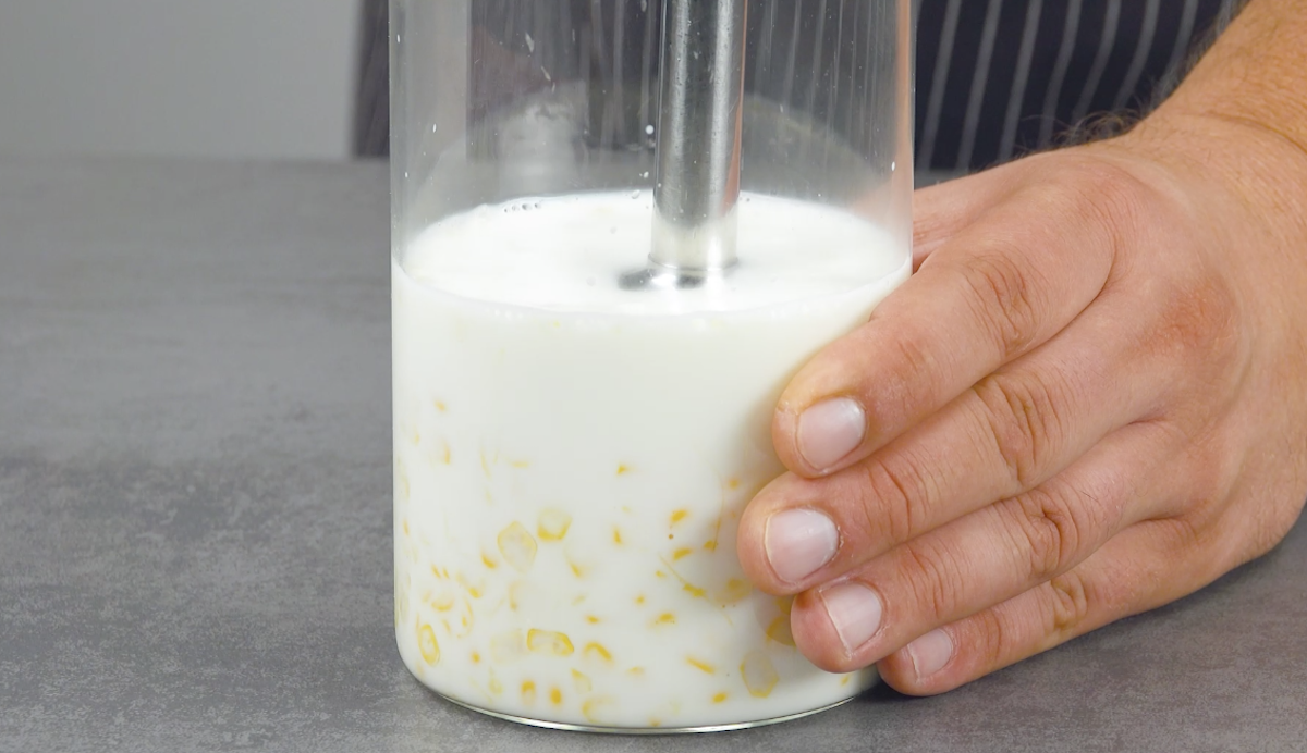 MaiskÃ¶rner werden zusammen mit Milch in hohem GefÃ¤ÃŸ pÃ¼riert