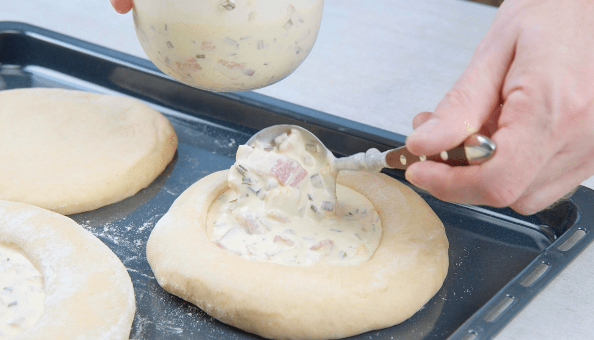 Quiche-Masse wird in Teigringe auf Backblech gefÃ¼llt