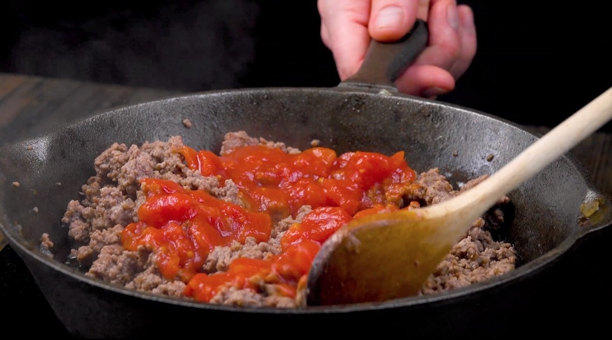 Hackfleisch wird samt passierten Tomaten in Pfanne angebraten