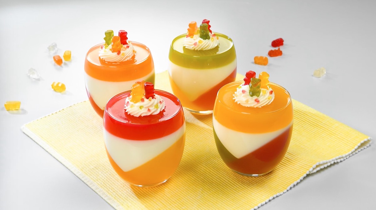 4 GlÃ¤ser GummibÃ¤rchen-Pannacotta auf Platzset aus Stoff mit Sahne und GummibÃ¤ren als Dekoration