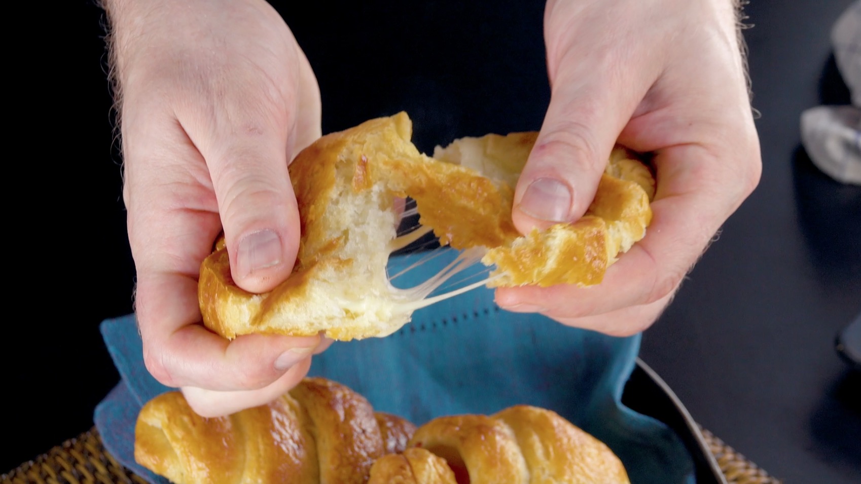 Selbstgemachtes KÃ¤se-Schinken-Croissant wird mit Fingern auseinander gezogen