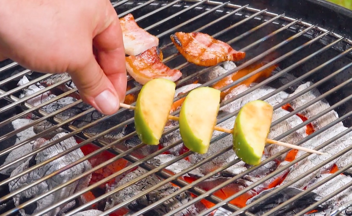 3 StÃ¼cke Bacon und 3 ApfelstÃ¼cke am SpieÃŸ auf dem Grill