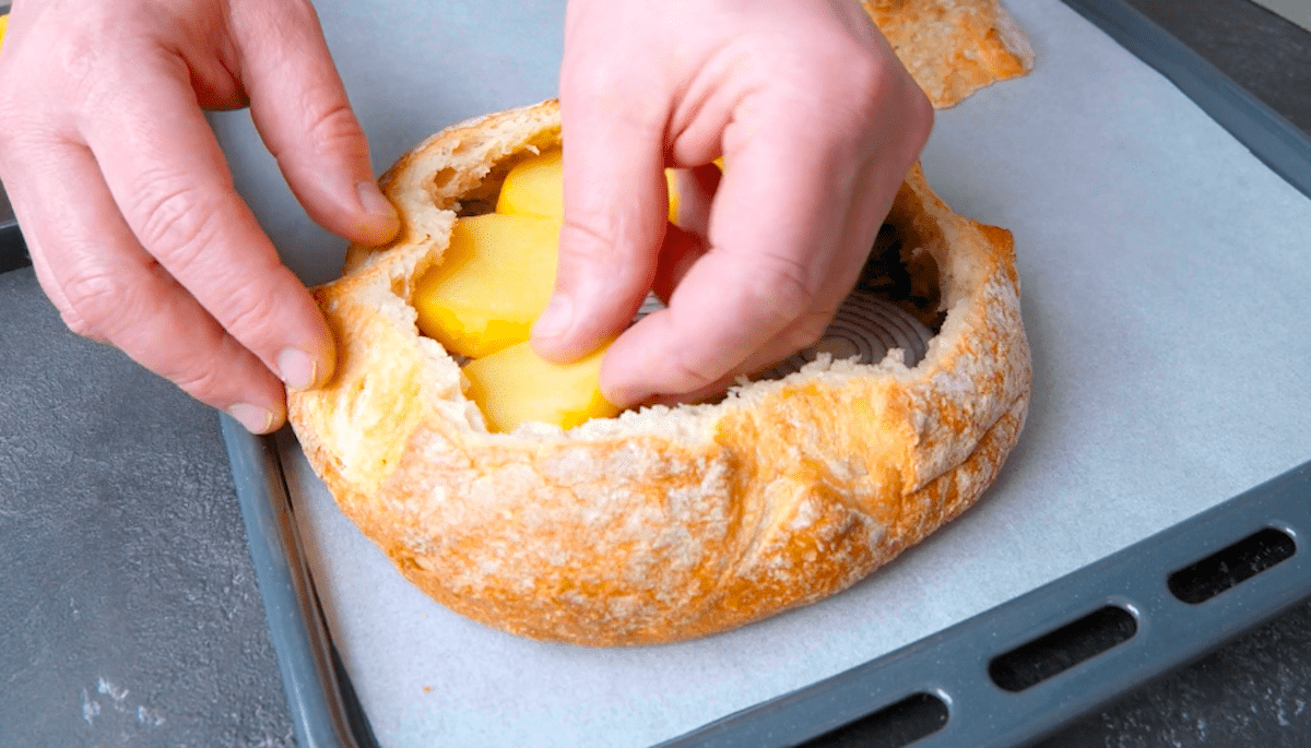 Ein rundes, ausgehÃ¶hltes WeiÃŸbrot wird mit Spinat, Zwiebeln und Kartoffeln gefÃ¼llt.