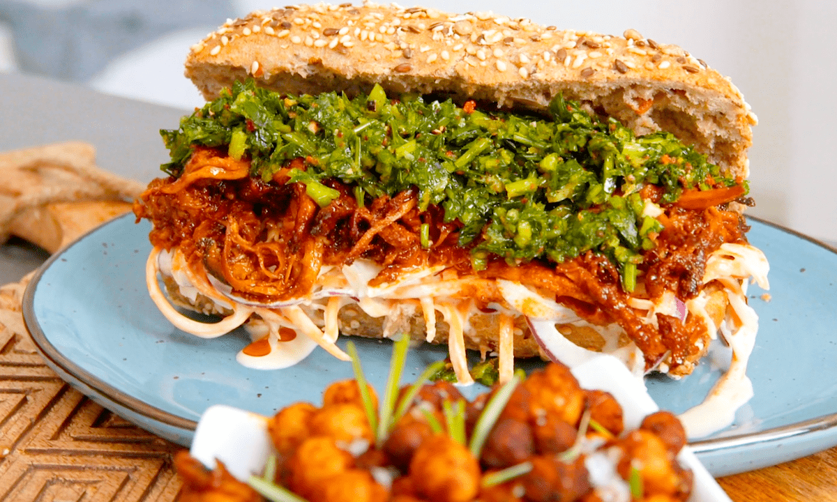 Kräuterseitlinge im Baguettebrötchen mit Krautsalat und Gremolata auf einem Teller.