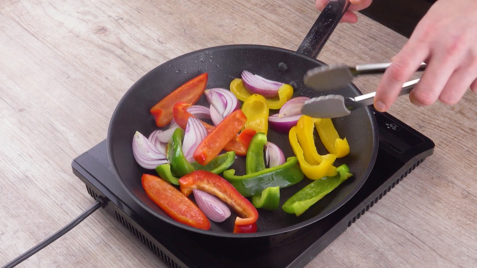 Paprika- und Zwiebelstreifen werden in Pfanne angebraten