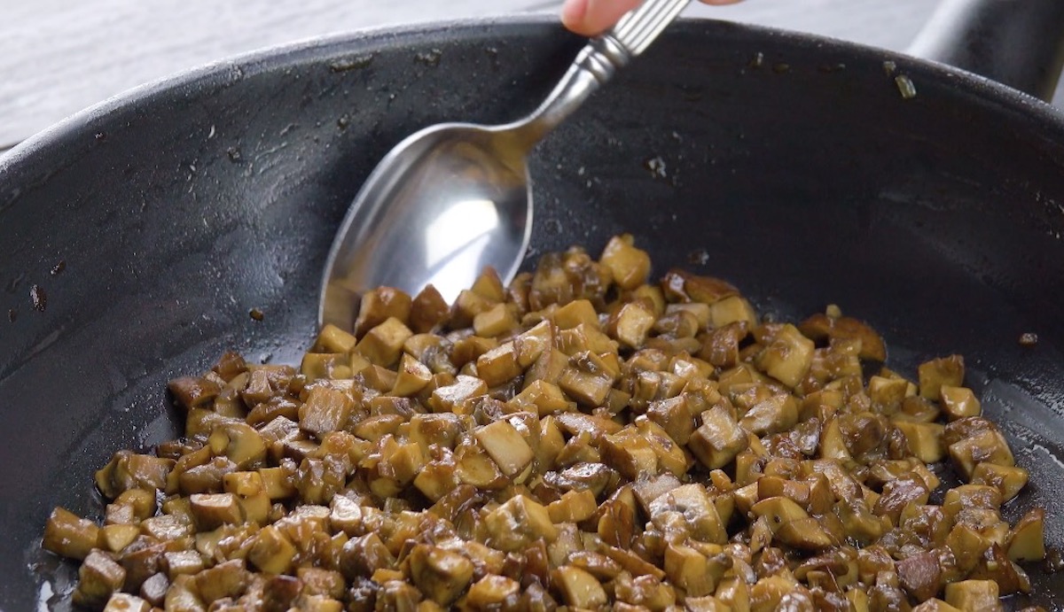 In WÃ¼rfel geschnittene Champignons werden in Pfanne angebraten