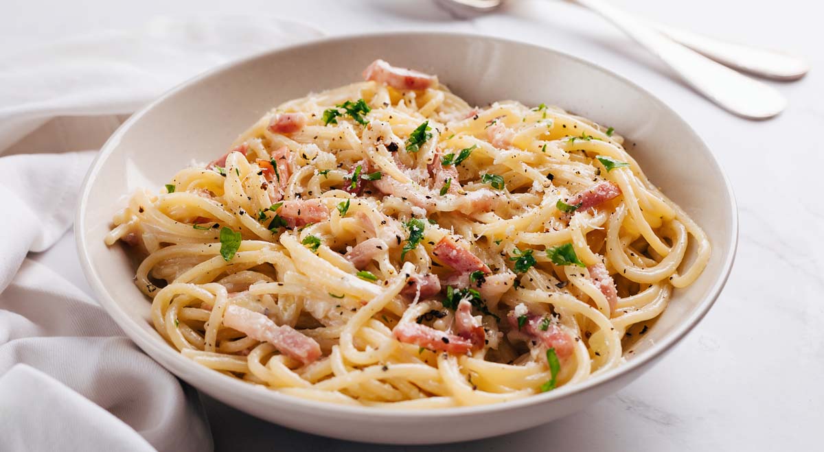 Eine weiße Schüssel mit französischer Spaghetti Carbonara.