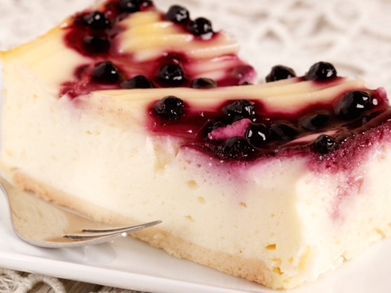 Ein Stück gestrudelter Käsekuchen vom Blech mit Blaubeeren.