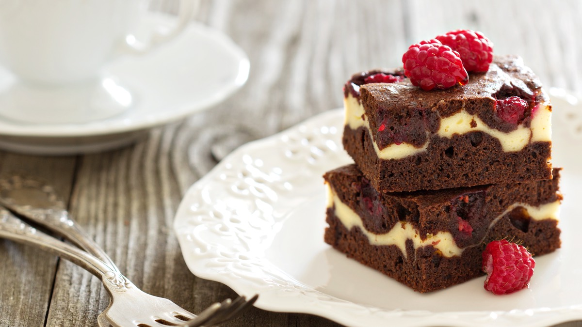 Zwei Himbeer-Cheesecake-Brownies übereinander auf einem Teller.