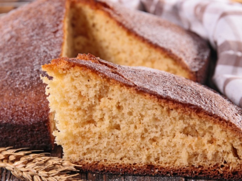 Ein Stück Joghurtkuchen liegt vor dem restlichen Kuchen.