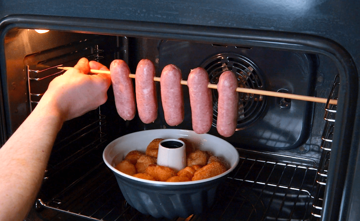 AufgespieÃŸte BratwÃ¼rste werden in einen Ofen Ã¼ber eine mit HefebÃ¤llchen gefÃ¼llte Gugelhupfform gehangen