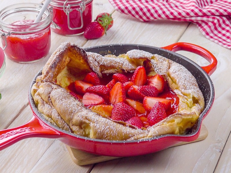 Riesiger Ofen-Pfannkuchen mit frischen Erdbeeren in roter Pfanne: