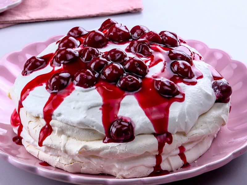 Rosa Teller mit Pavlova mit Kirschen