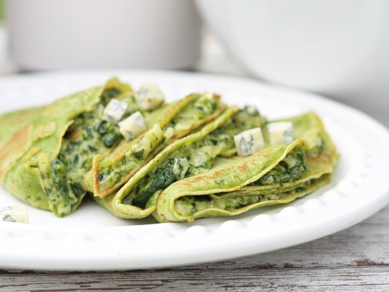 Spinatpfannkuchen mit Gorgonzola-Spinat-Füllung auf einem weißen Teller.