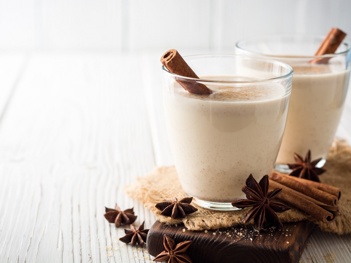 2 GlÃ¤ser GlÃ¼hwein mit Portwein und Sahne, garniert mit einer Zimtstange, daneben Zimtstangen und Anissterne.