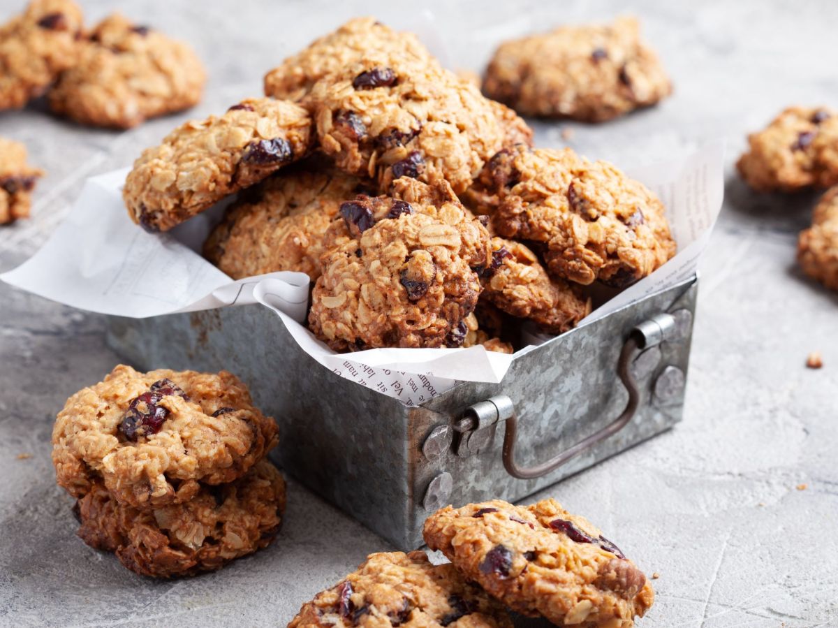 Cookies in einer Keksdose, daneben liegen noch mehr Kekse.