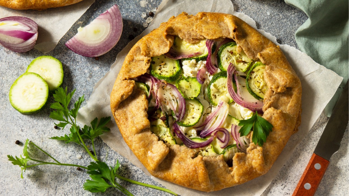 Zucchini-Galette mit roten Zwiebeln und Feta von oben, daneben frische Petersilie