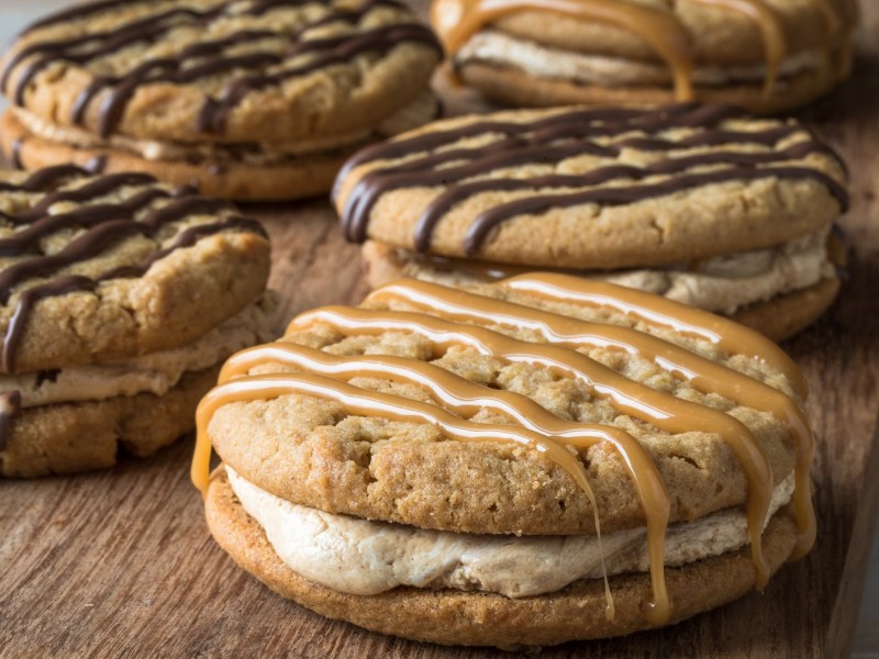 Marshmallow-Plätzchen als Dopperdecker-Kekse auf einem Brett, verziert mit Karamell- und Schokosoße.