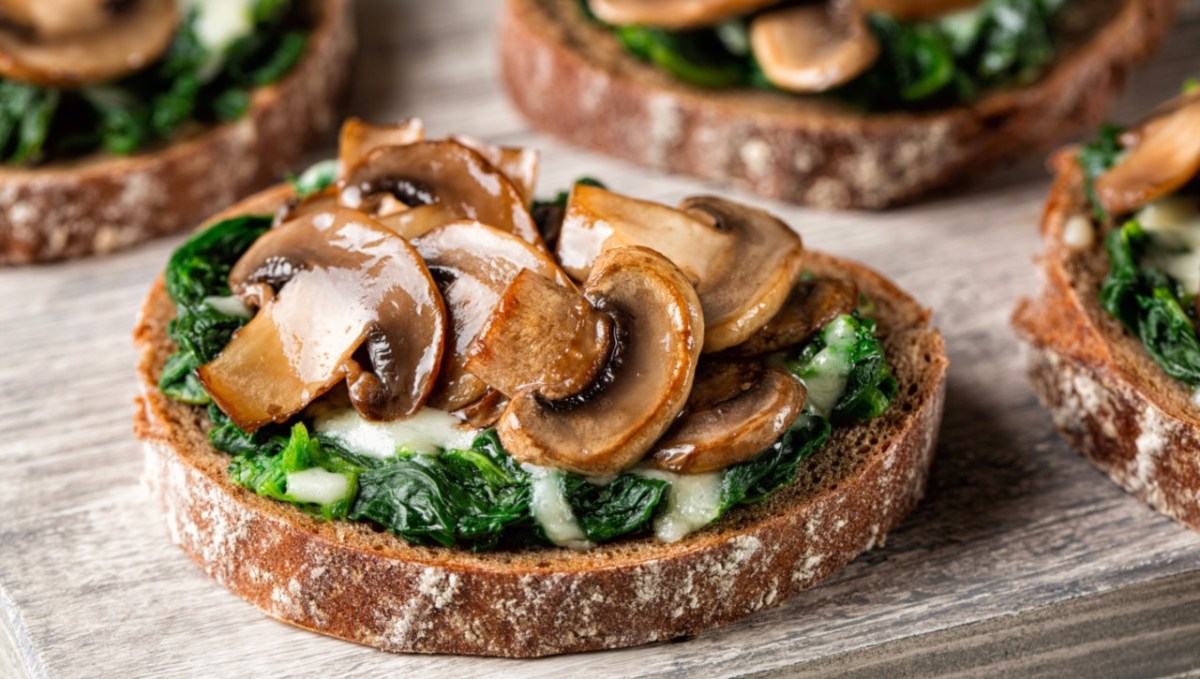 Mehrere Portionen Champignon-Bruschetta mit Ricotta und frischen Kräutern.