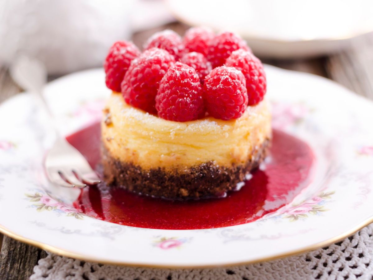 Käsekuchen-Muffins mit Himbeeren auf einem Himbeerspiegel.