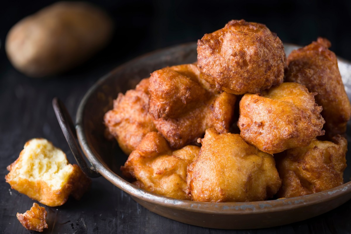 Frittierte Kartoffelkrapfen in einer kleinen Kupferpfanne auf dunklem Untergrund