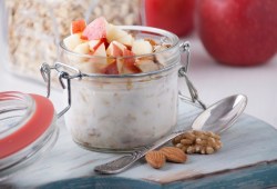 Ein Glas mit Deckel und Bircher Müsli auf einem hellen Tisch.