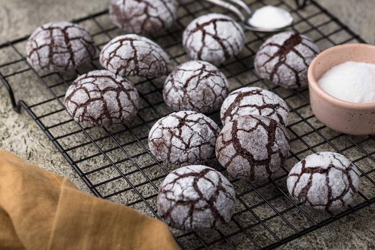 Chocolate Crinkle Cookies auf einem Backgitter mit Puderzucker