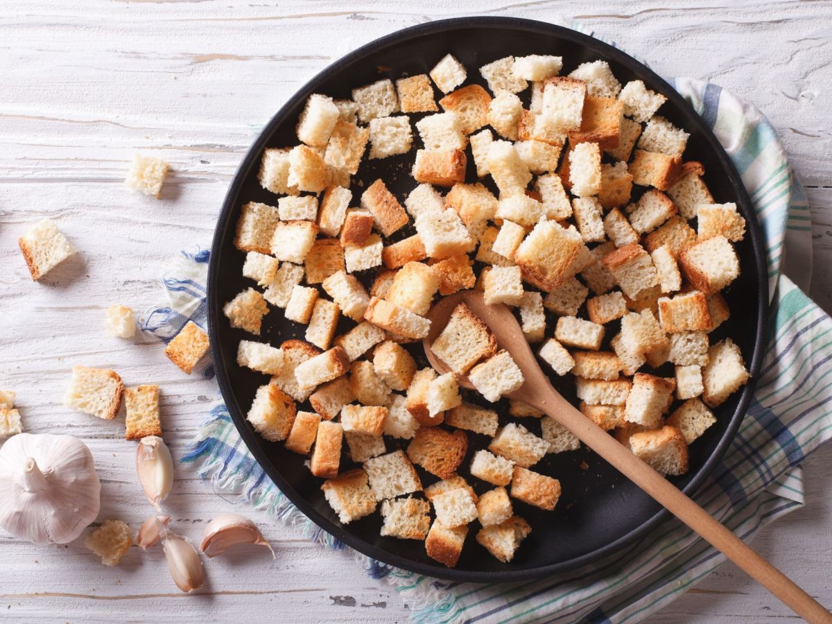 Croutons selber machen in der Pfanne, darin liegt ein HolzlÃ¶ffel. Einige Croutons liegen als Deko auÃŸen um die Pfanne.