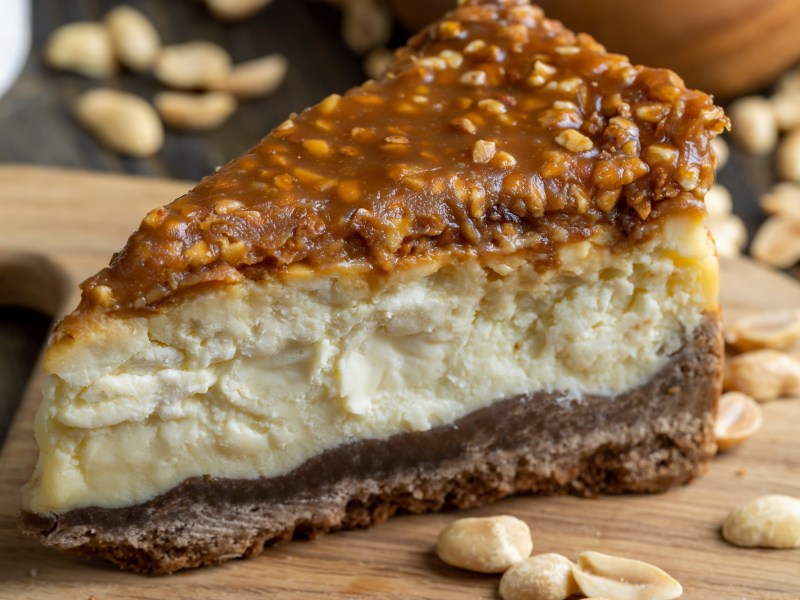 Ein Stück Erdnussbutter-Cheesecake mit Schoko-Karamell-Erdnussbelag.