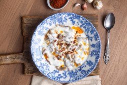 Falsche Manti auf einem blau gemusterten Teller mit Joghurtsoße und Paprika-Butter