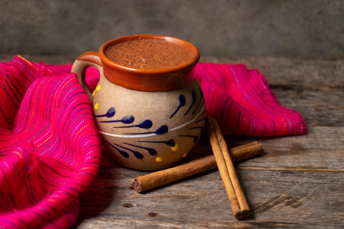 Mexikanische heiÃŸe Schokolade in einer traditionellen Tasse mit Zimtstangen.