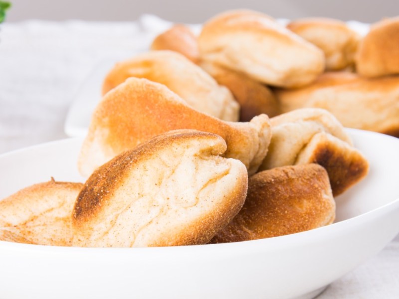 Ein Stapel Pan de Sal in einer Schüssel. Im Hintergrund sind mehr zu sehen.