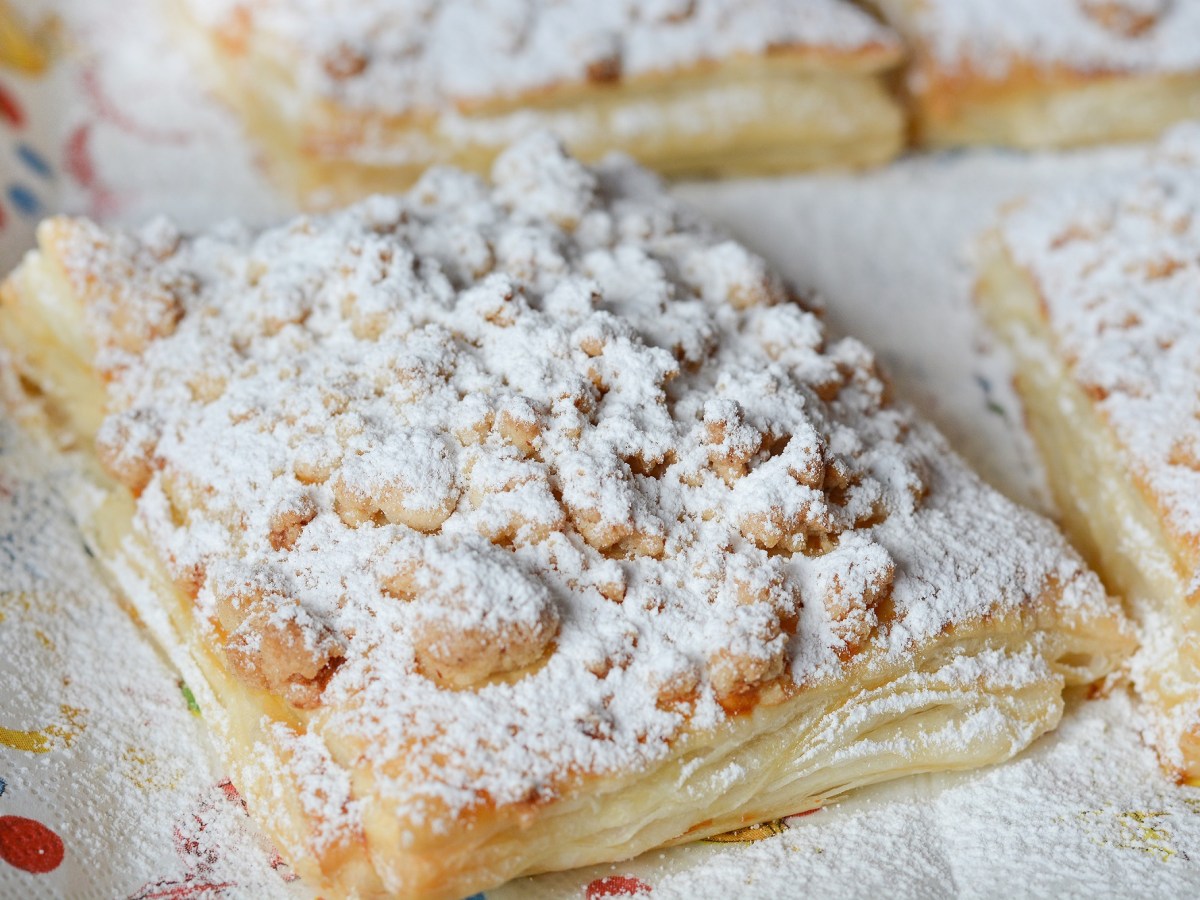 Prasselkuchen-Rezept: Ein Stück Prasselkuchen mit Streuseln und Puderzucker, Nahaufnahme.