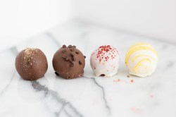 4 Red-Velvet-Pralinen mit Schokoladenüberzug auf einer weißen Marmorplatte.