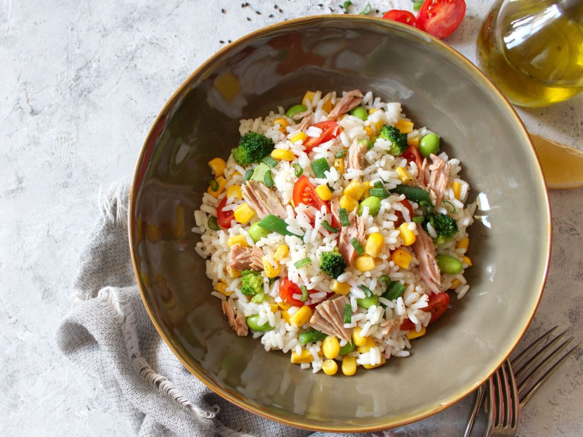 Reissalat mit Thunfisch in einem großen Teller. Eine Serviette liegt als Deko unter dem Teller.