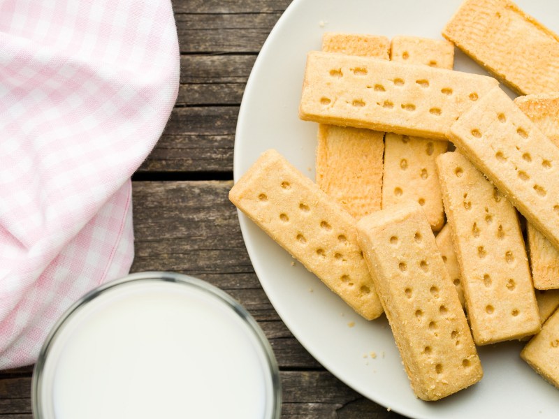 Blick von oben auf einen Teller mit Shortbread-Keksen und einem Glas Milch daneben.