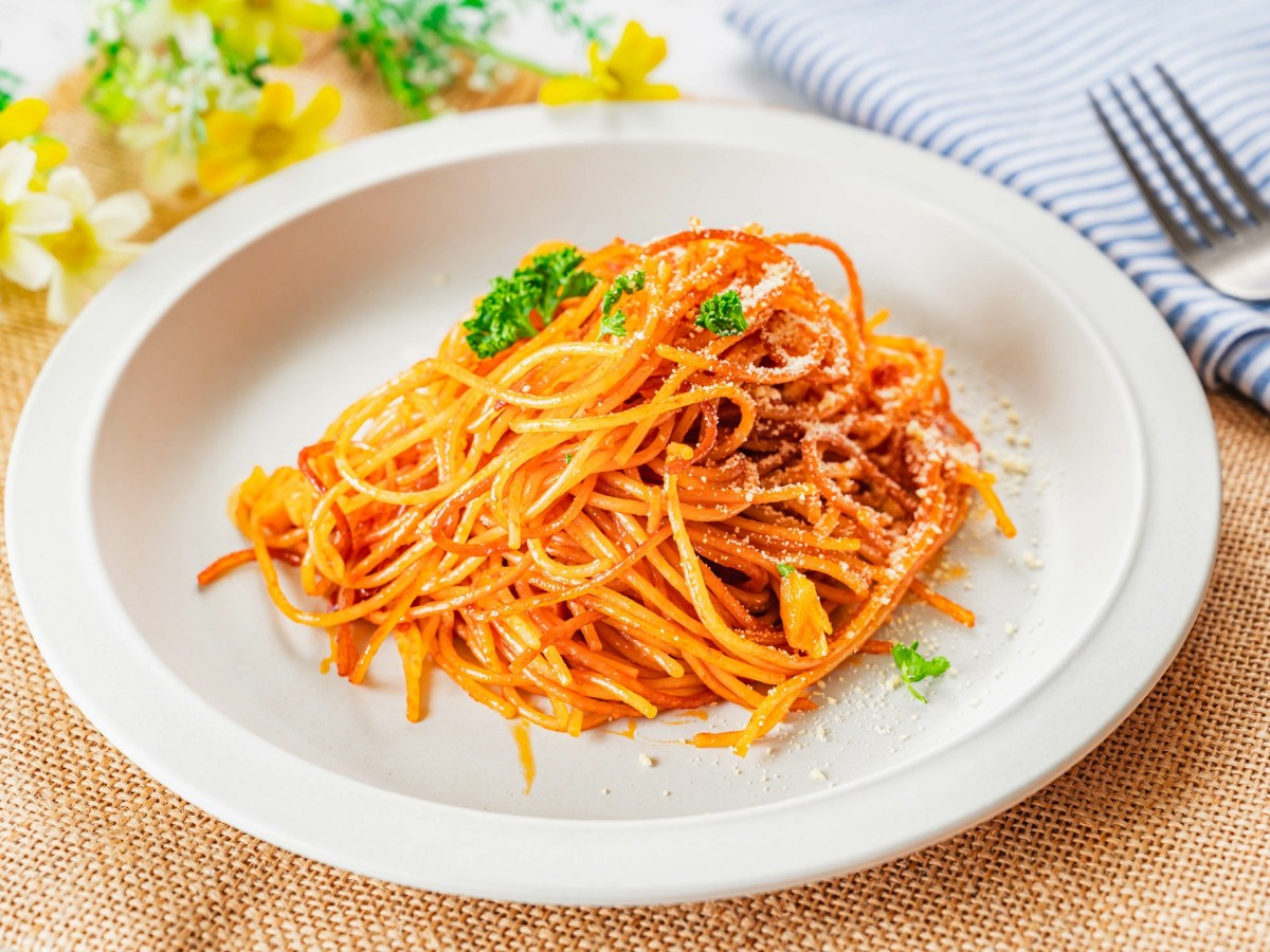 Spaghetti all'Assassina auf einem weißen Teller, daneben liegt eine Gabel.