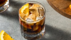 Ein Glas Sparkling Americano mit Eiswürfeln und einer Orangenscheibe.