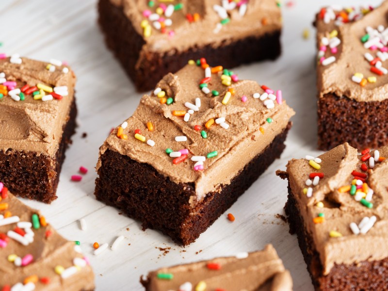 verschiedene Stücke Brownies mit Mokka-Frosting und Zuckerstreuseln auf hellem Untergrund