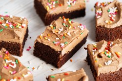 verschiedene Stücke Brownies mit Mokka-Frosting und Zuckerstreuseln auf hellem Untergrund