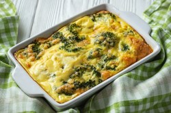 Kartoffel-Brokkoli-Gratin ohne Vorkochen in einer Auflaufform, darum ist ein grün-weiß kariertes Geschirrtuch drapiert.