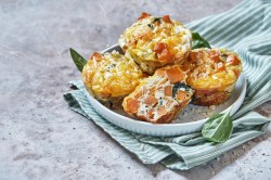 4 Kroketten-Muffins mit Gemüse und Schmand auf einem Teller, der auf einem gestreiften Geschirrtuch steht.