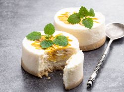 Zwei Mini-Cheesecakes mit Mango; eins ist angeschnitten.